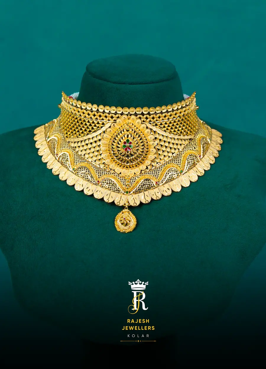 A broad gold bridal collar with a stone-set centre, on deep teal velvet.