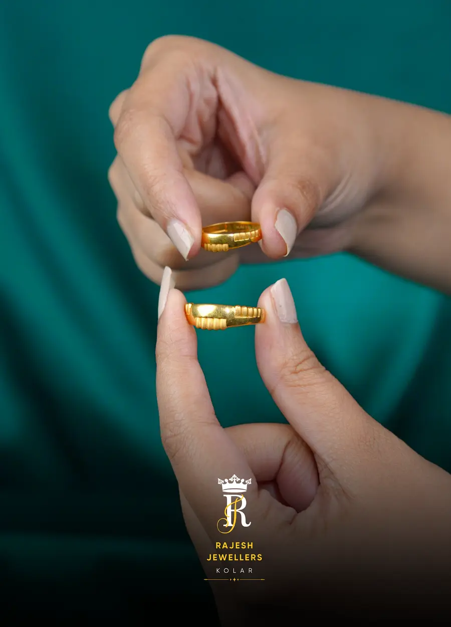 Two plain gold bands held between two hands against teal cloth.